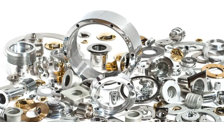 Una collezione di componenti metallici di precisione, alcuni lucidi, altri dorati. La loro accuratezza dimensionale è misurata in cosa sono i micron, essenziali per l'ingegneria moderna.