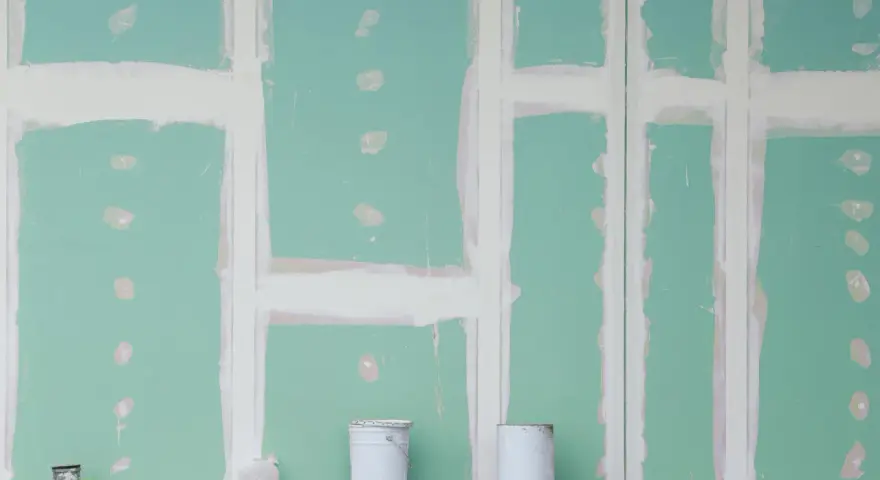 Pareti in cartongesso in fase di finitura, con stuccatura delle giunzioni. Si nota lo spessore delle pareti in cartongesso e due secchi di vernice.