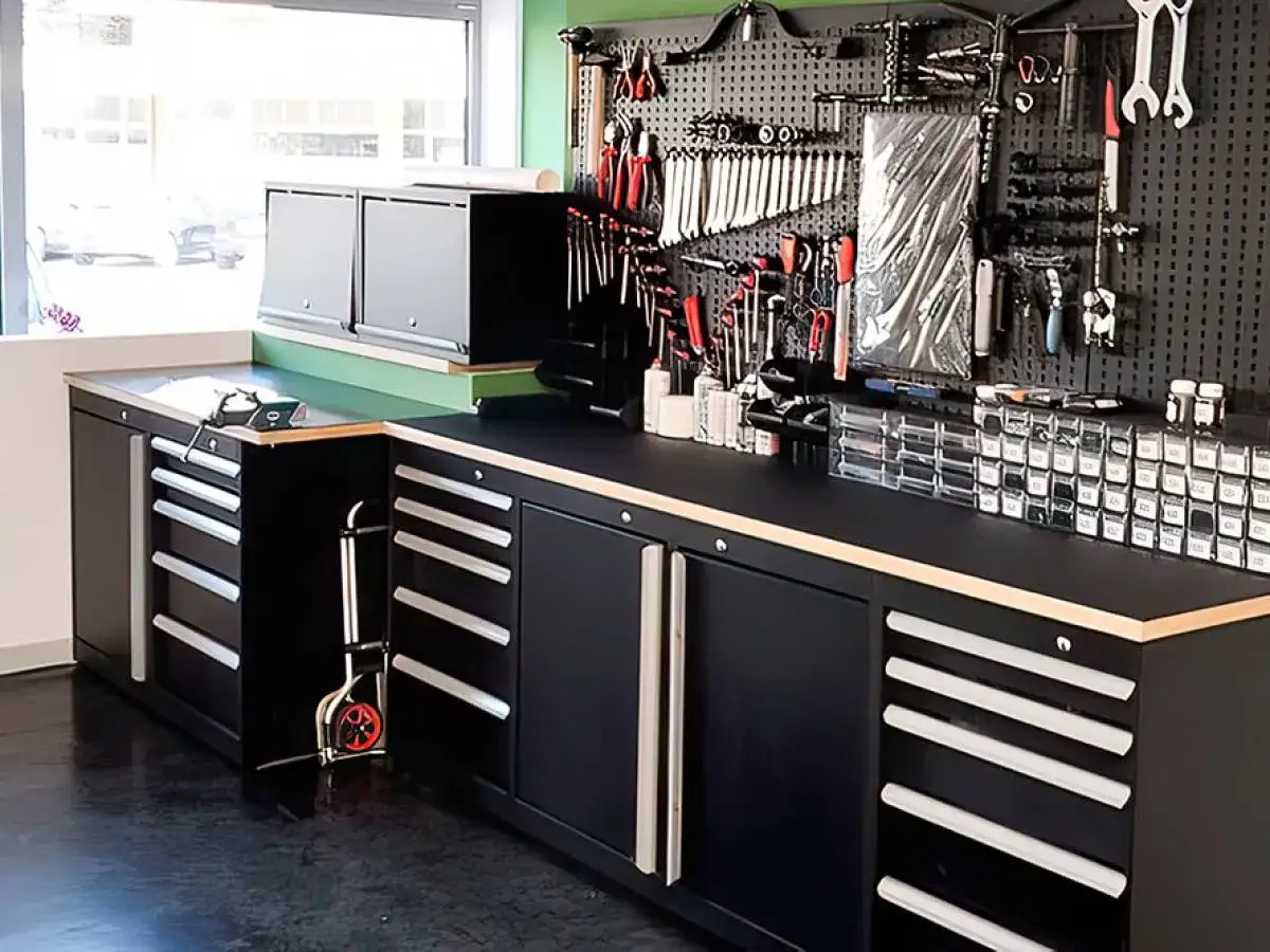 Banco da lavoro nero con cassetti e pannello porta attrezzi, ideale per organizzare officina.