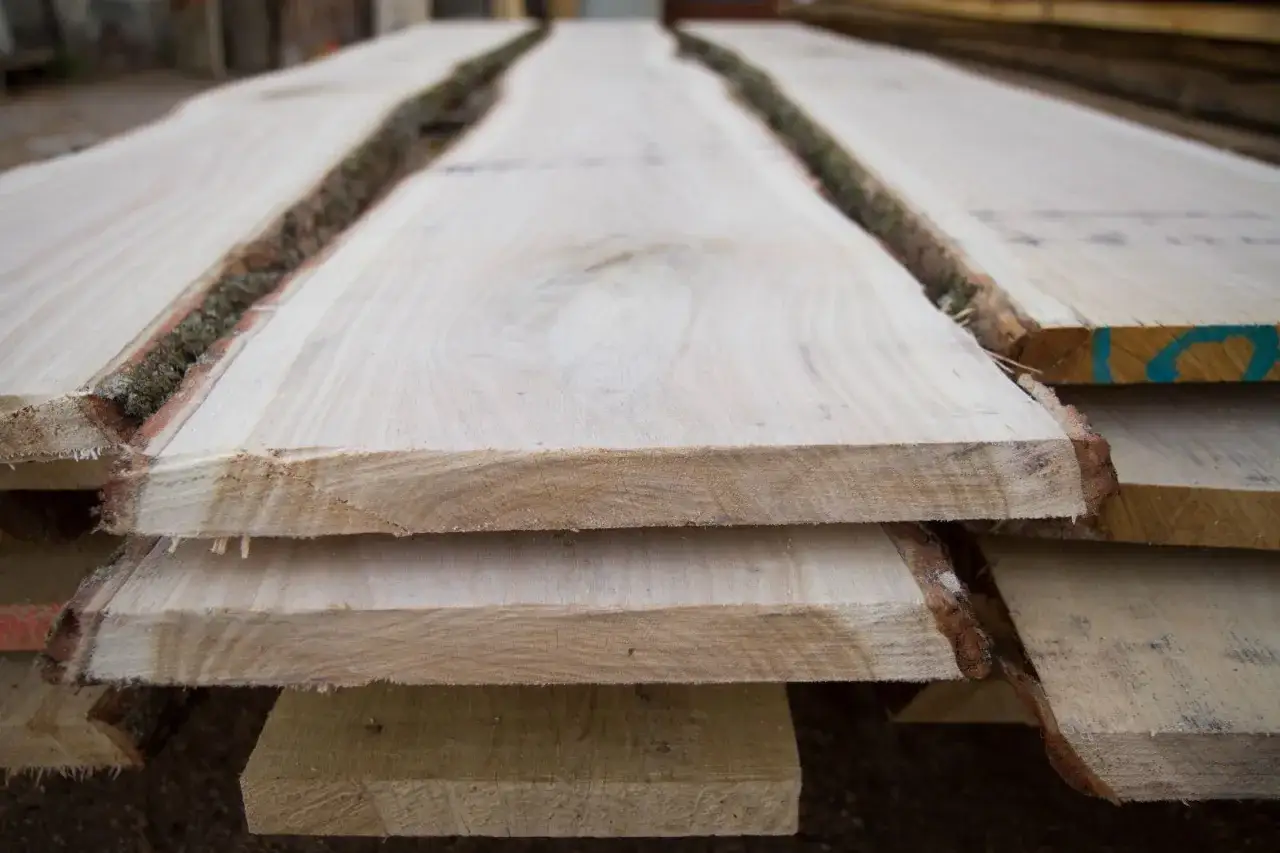Tavole di legno grezzo impilate, con la corteccia ancora presente, pronte per il processo di stagionatura che ne assicura la durabilit&agrave;.