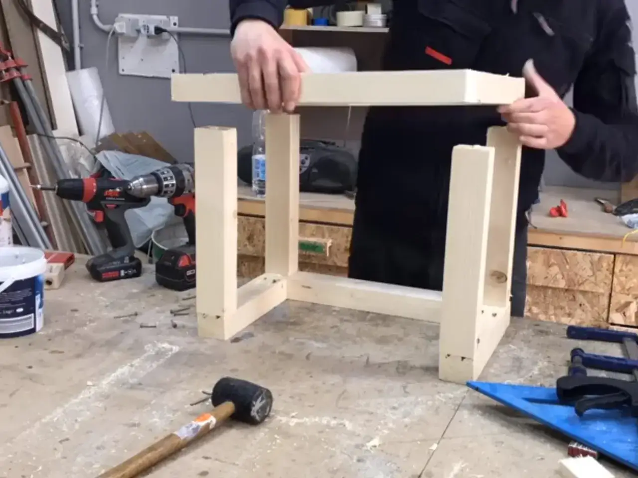 Costruzione di un banco fresa fai da te. Un uomo assembla la struttura in legno con viti e trapano.