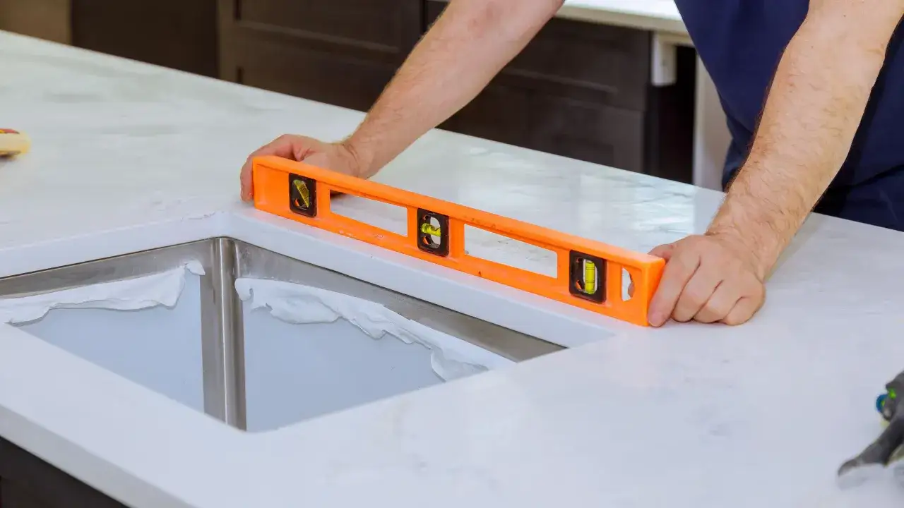 Installazione di un top cucina: un operaio usa una livella per assicurarsi che il piano sia perfettamente orizzontale prima di montare il lavello.