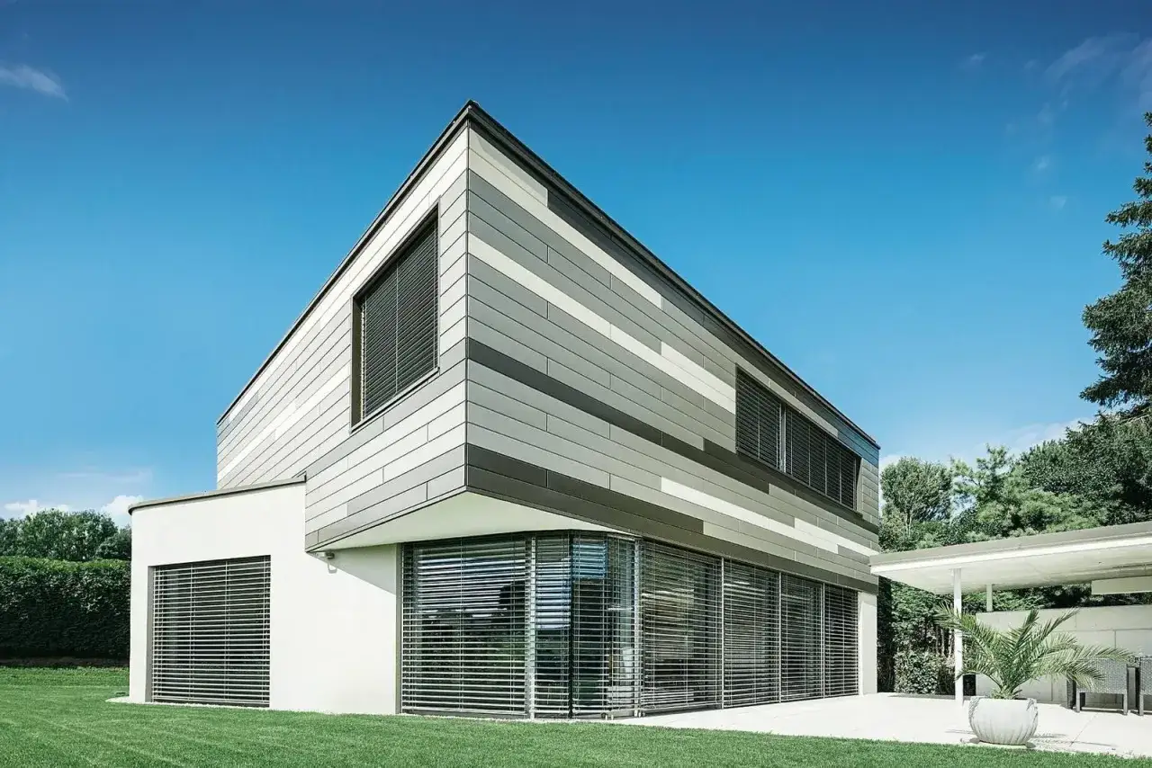 Moderna casa con facciata a fasce grigie e bianche, che mostra diversi tipi di intonaco per esterni.