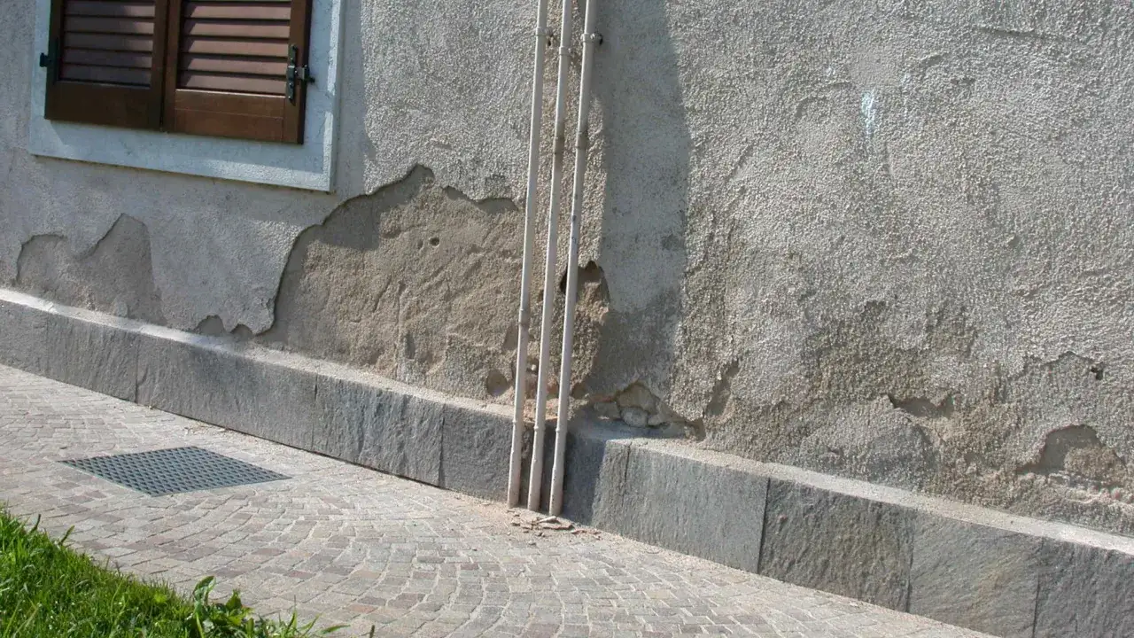 Muro con intonaco scrostato, mostra come rasare un muro rovinato per prepararlo alla riparazione.