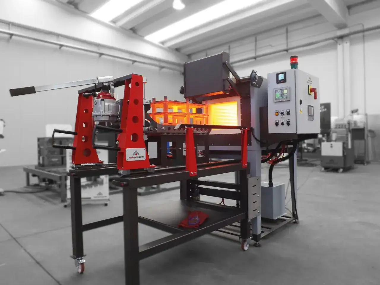 Forno industriale per la tempra dell'acciaio temprato, con carrello di carico e pannello di controllo.