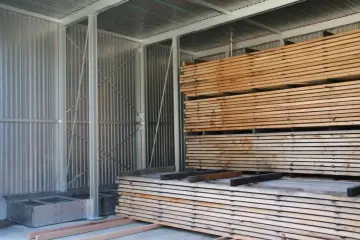 Legno impilato in un capannone, pronto per stagionare. Un progetto fai-da-te per conservare il legno.